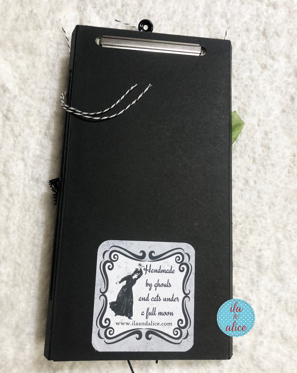 Black notebook with a decorative label on a textured white background
