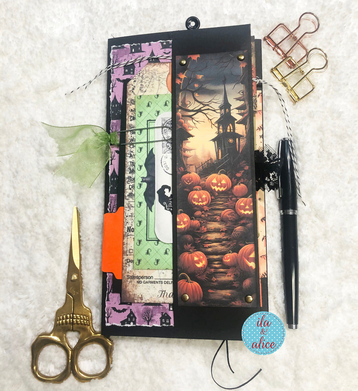 Halloween-themed folio with pumpkins, scissors, and a pen on a textured surface.