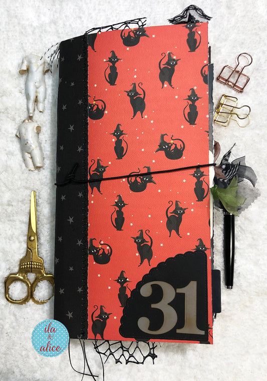 Handmade made junk journal with black cat pattern and number 31 on a n orange background, surrounded by decorative items.
