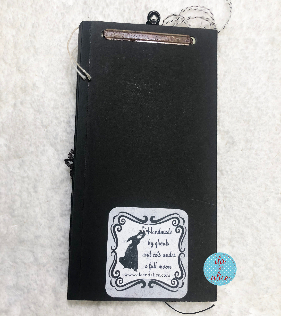 Black notebook with a decorative label on a textured white background
