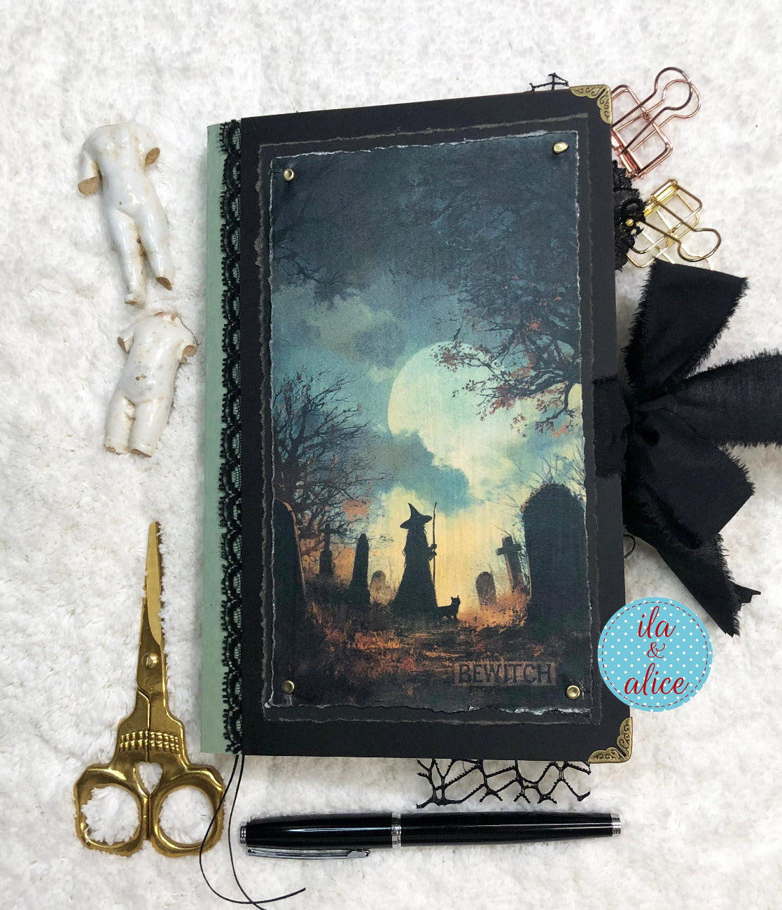 Handmade Eerie Halloween Gothic junk journal with a Halloween-themed cover, surrounded by decorative items on a textured surface.