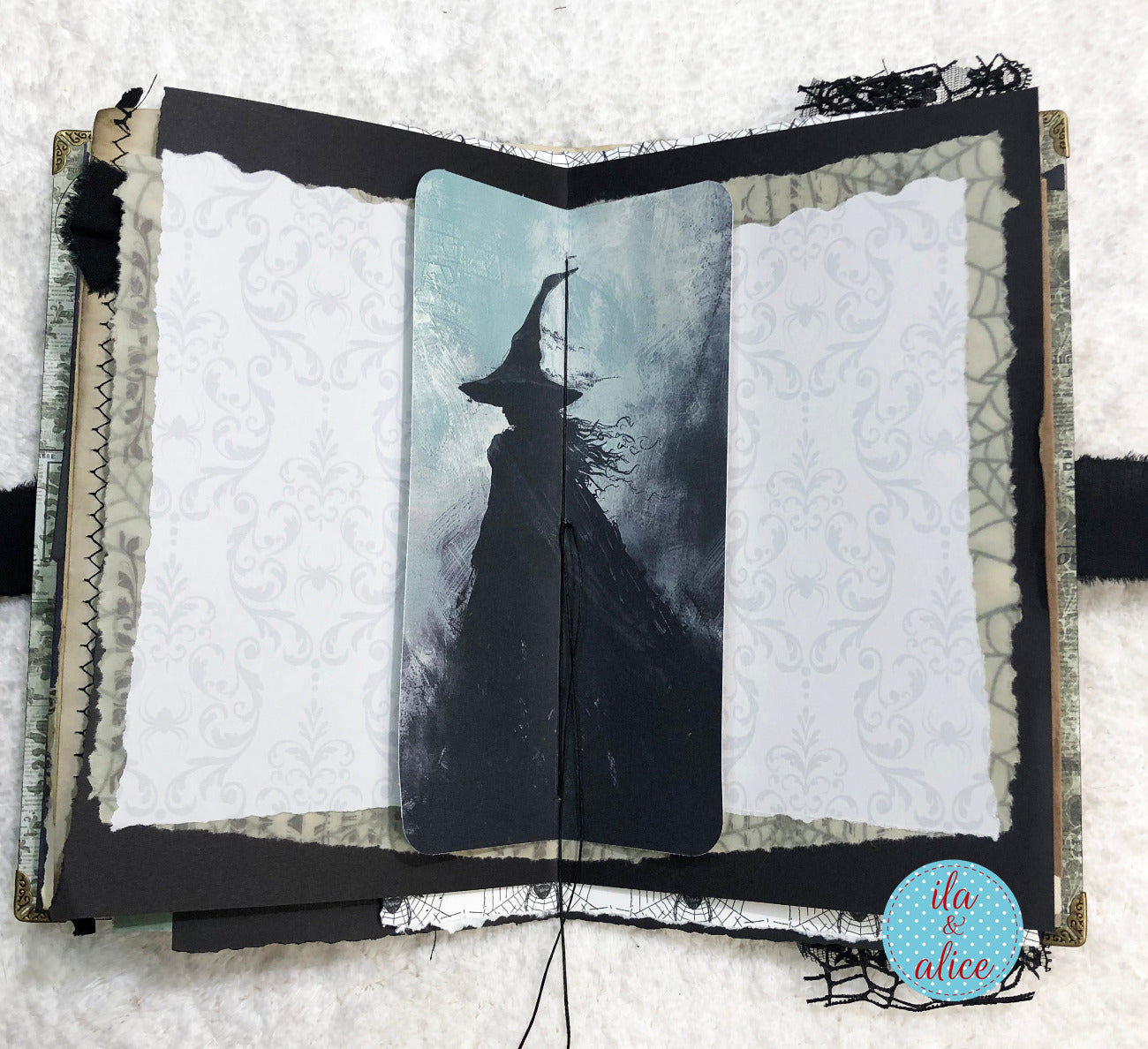 Handmade Eerie Halloween Gothic junk journal w artistic depiction of a witch in a hat and cloak inside an open book with decorative elements.