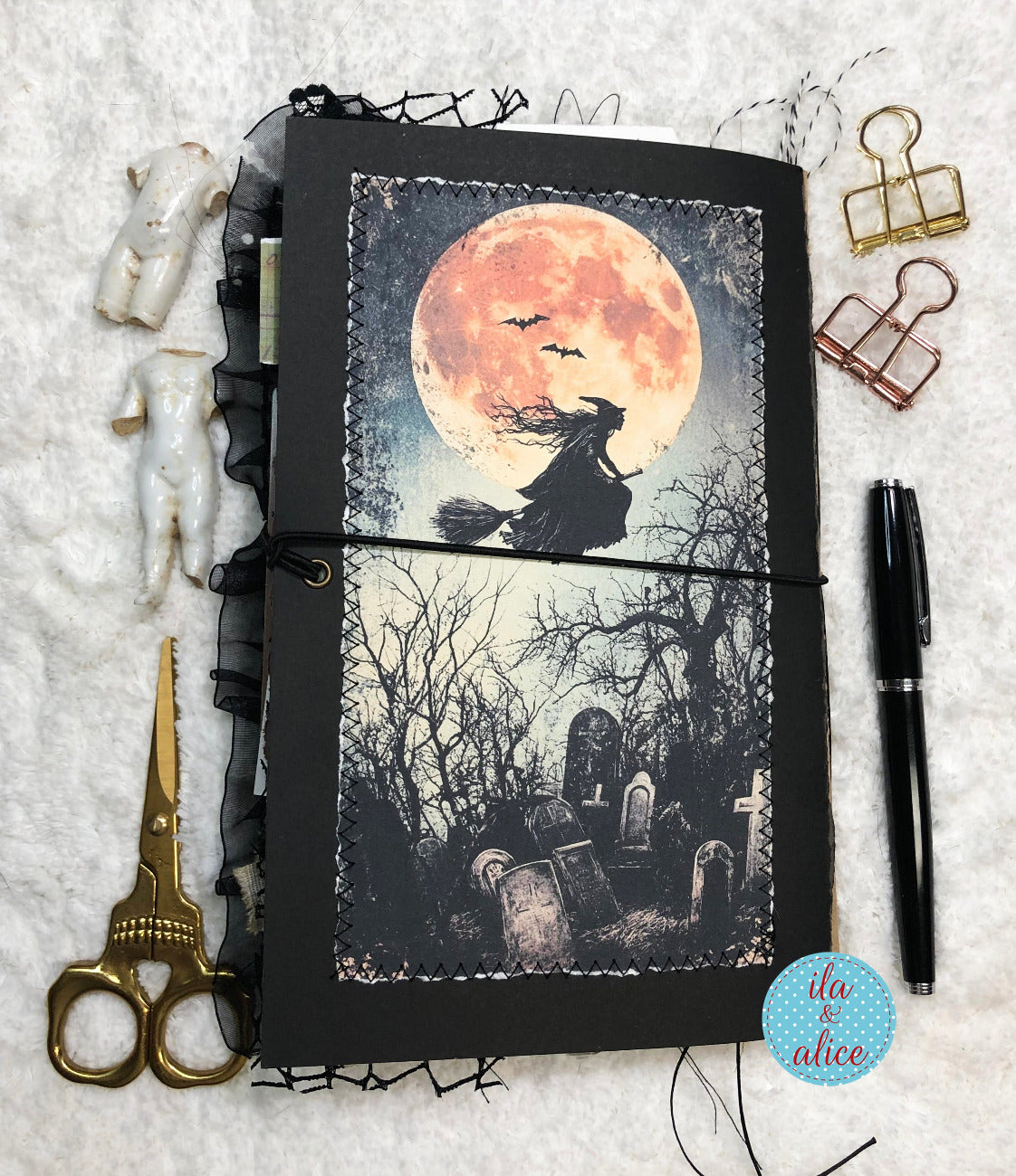 Handmade Halloween junk journal with Halloween-themed design featuring a witch and moon on a textured surface with stationery items.