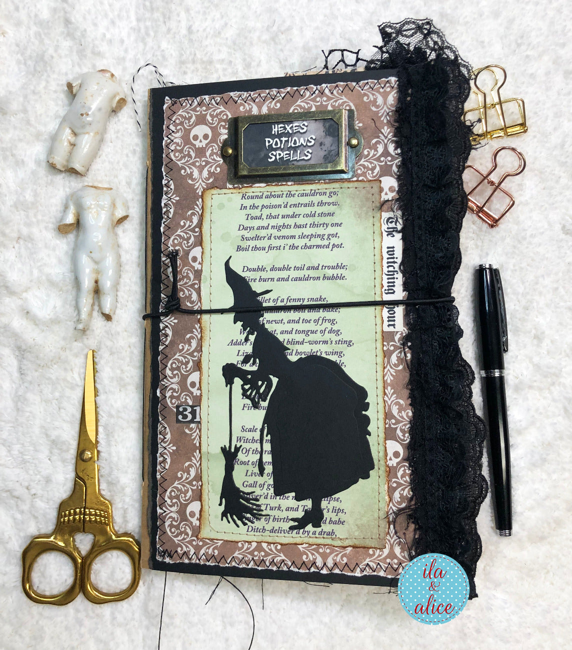Handmade Halloween junk journal with witch silhouette and text, surrounded by decorative items on a textured surface.