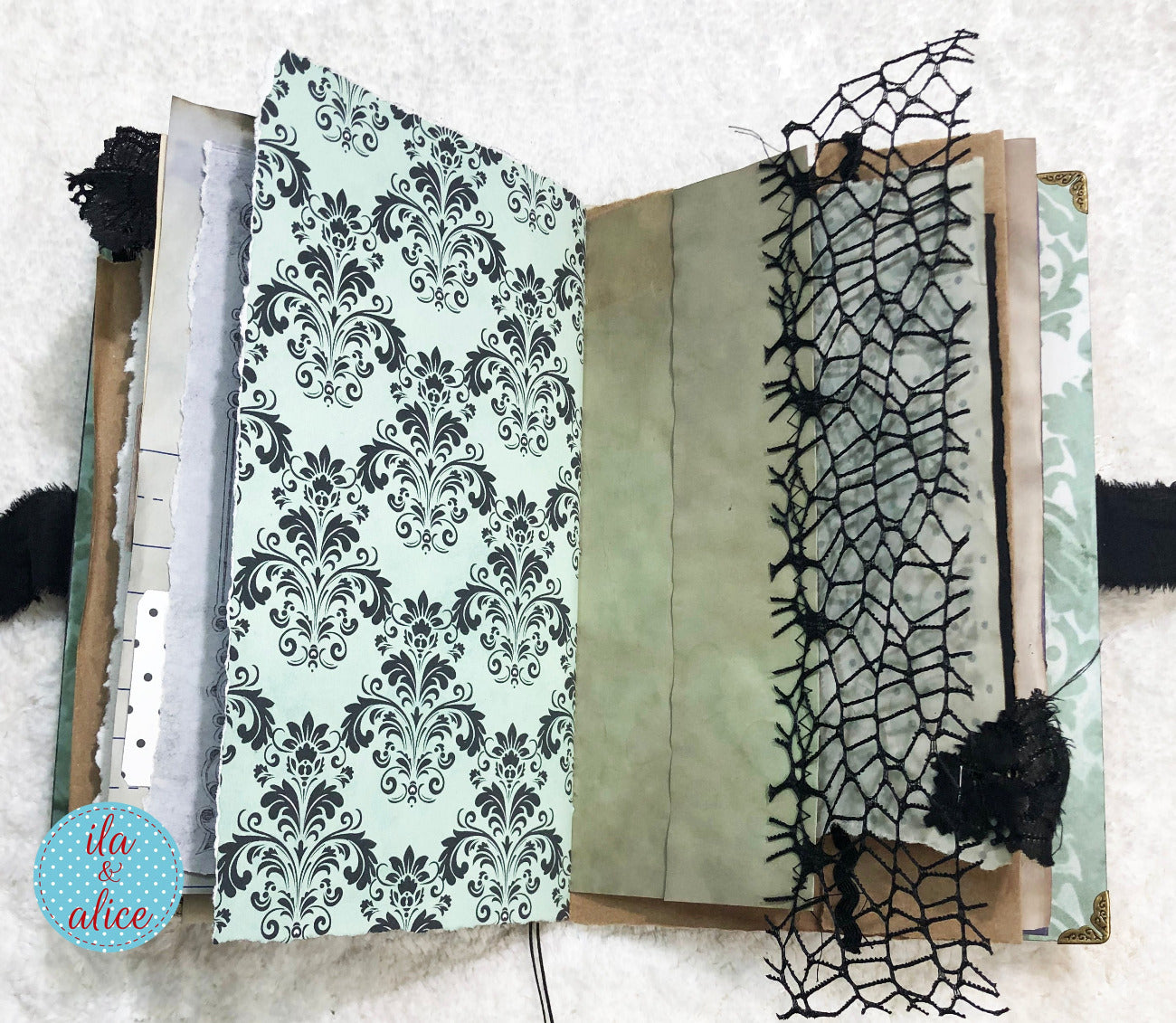 Handmade Eerie Halloween Gothic junk journal with patterned pages and spider web design on a textured surface.