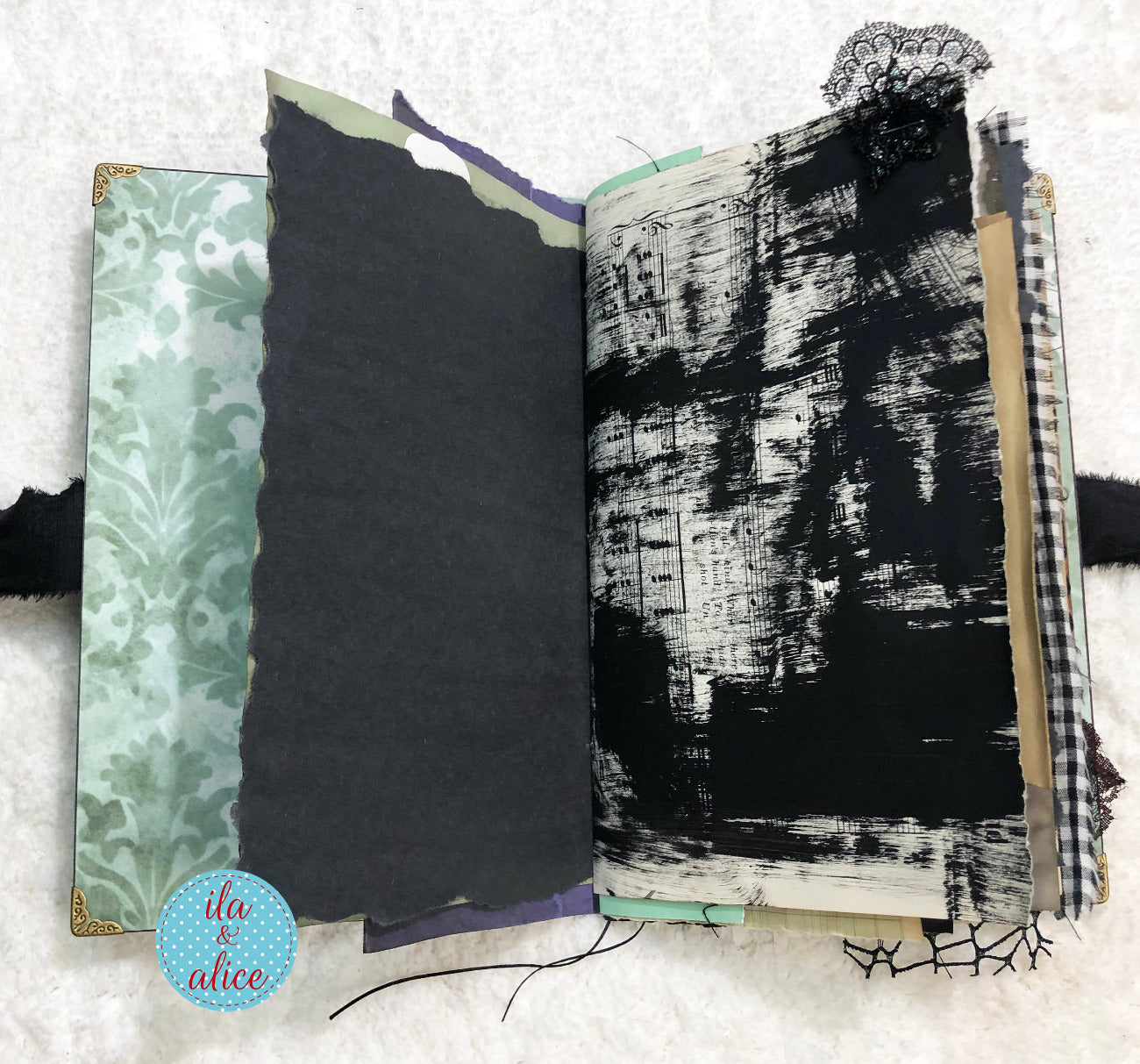 Handmade Eerie Halloween Gothic junk journal with textured pages on a textured surface, featuring a brand logo in the corner.