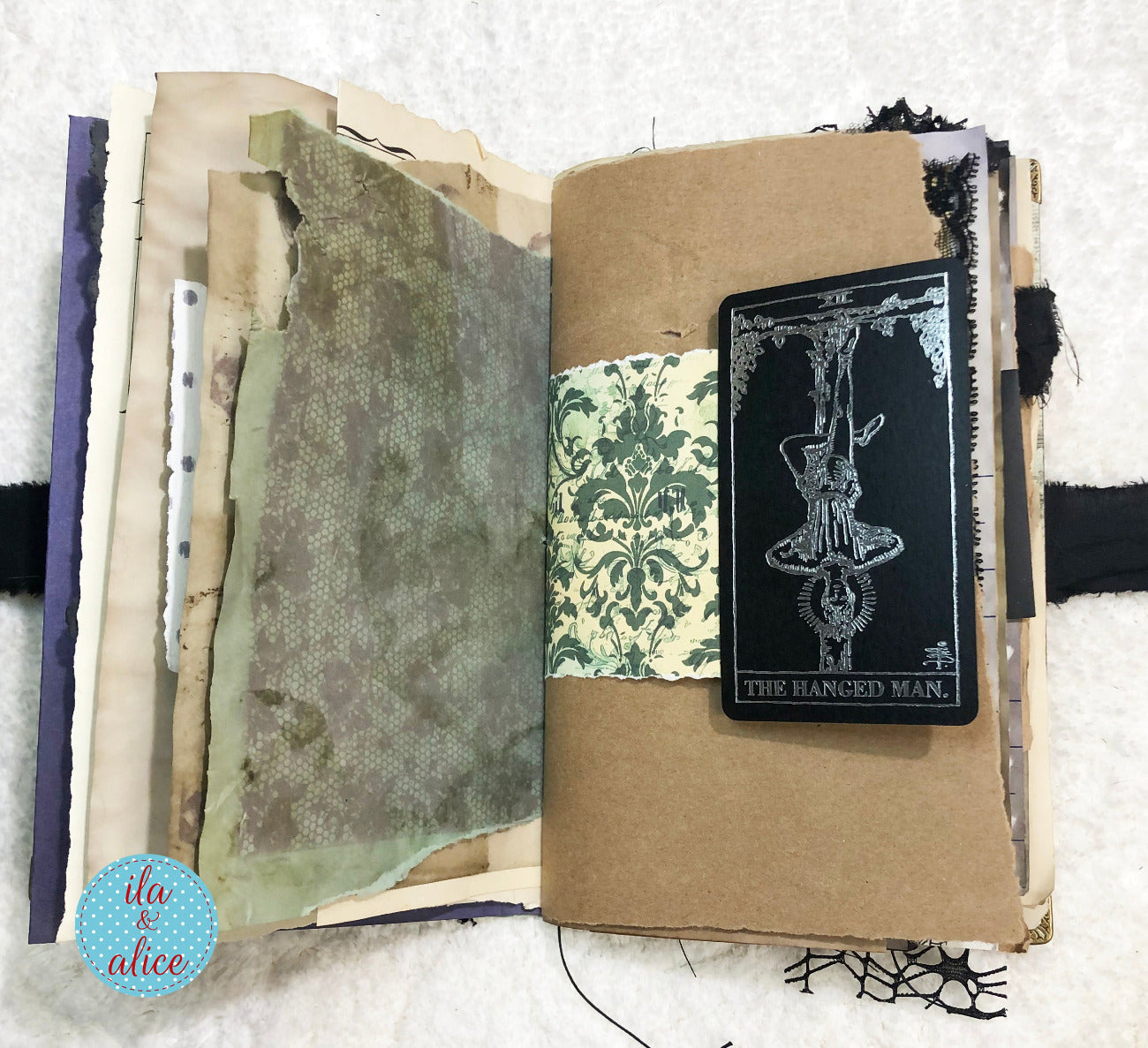 Handmade Eerie Halloween Gothic junk journal with textured pages and a tarot card titled 'The Hanged Man' on a textured white background.