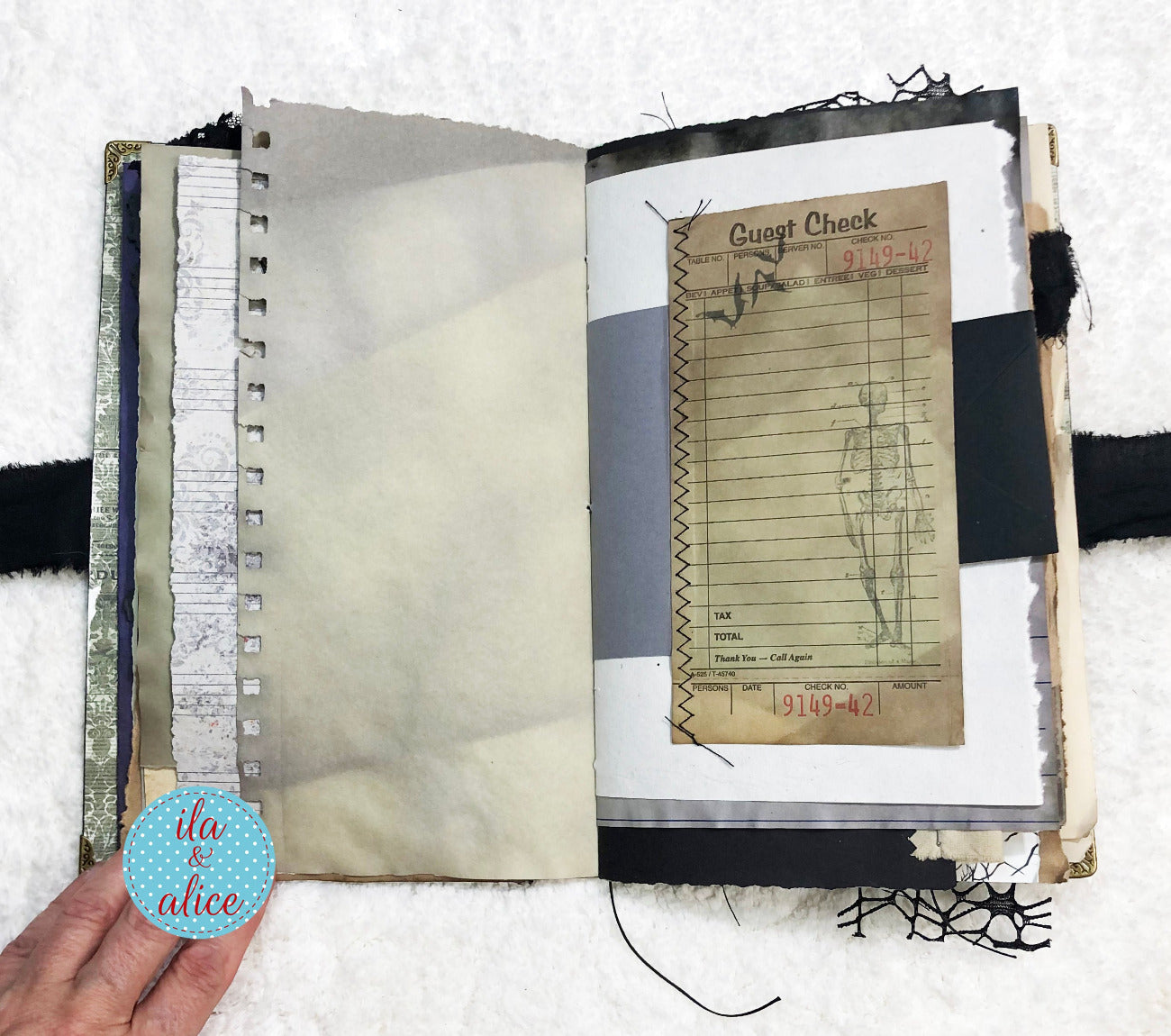 Handmade Eerie Halloween Gothic junk journal with vintage-style page featuring a 'Guest Check' slip, held by a hand with 'ila & alice' branding.