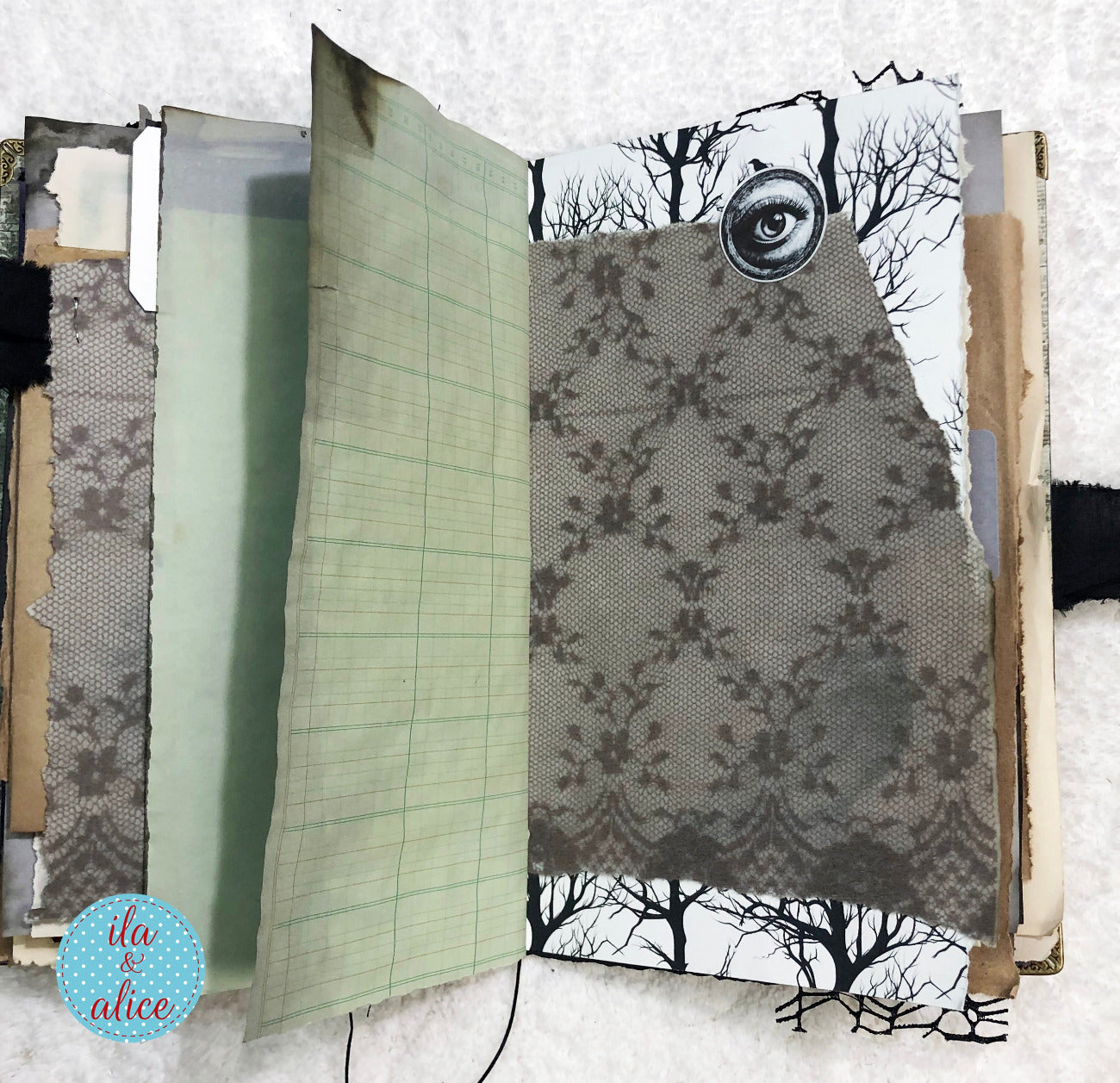 Handmade Eerie Halloween Gothic junk journal w collage of patterned paper with a tree and eye design on a white background