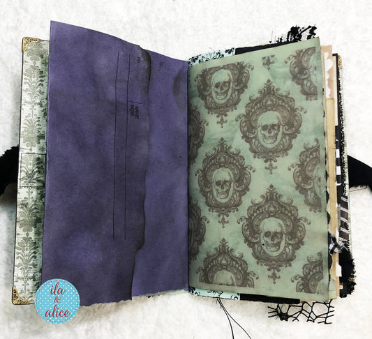 Handmade Eerie Halloween Gothic junk journal with skull pattern on a textured surface, featuring the brand 'ila & alice'.