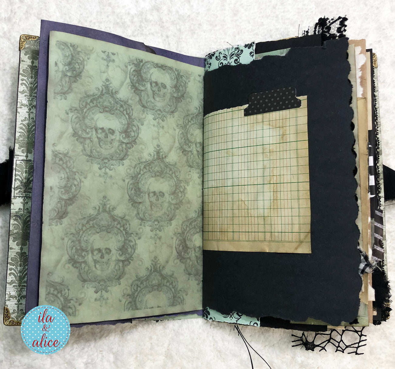 Handmade Eerie Halloween Gothic junk journal with decorative pages and grid paper on a textured surface.