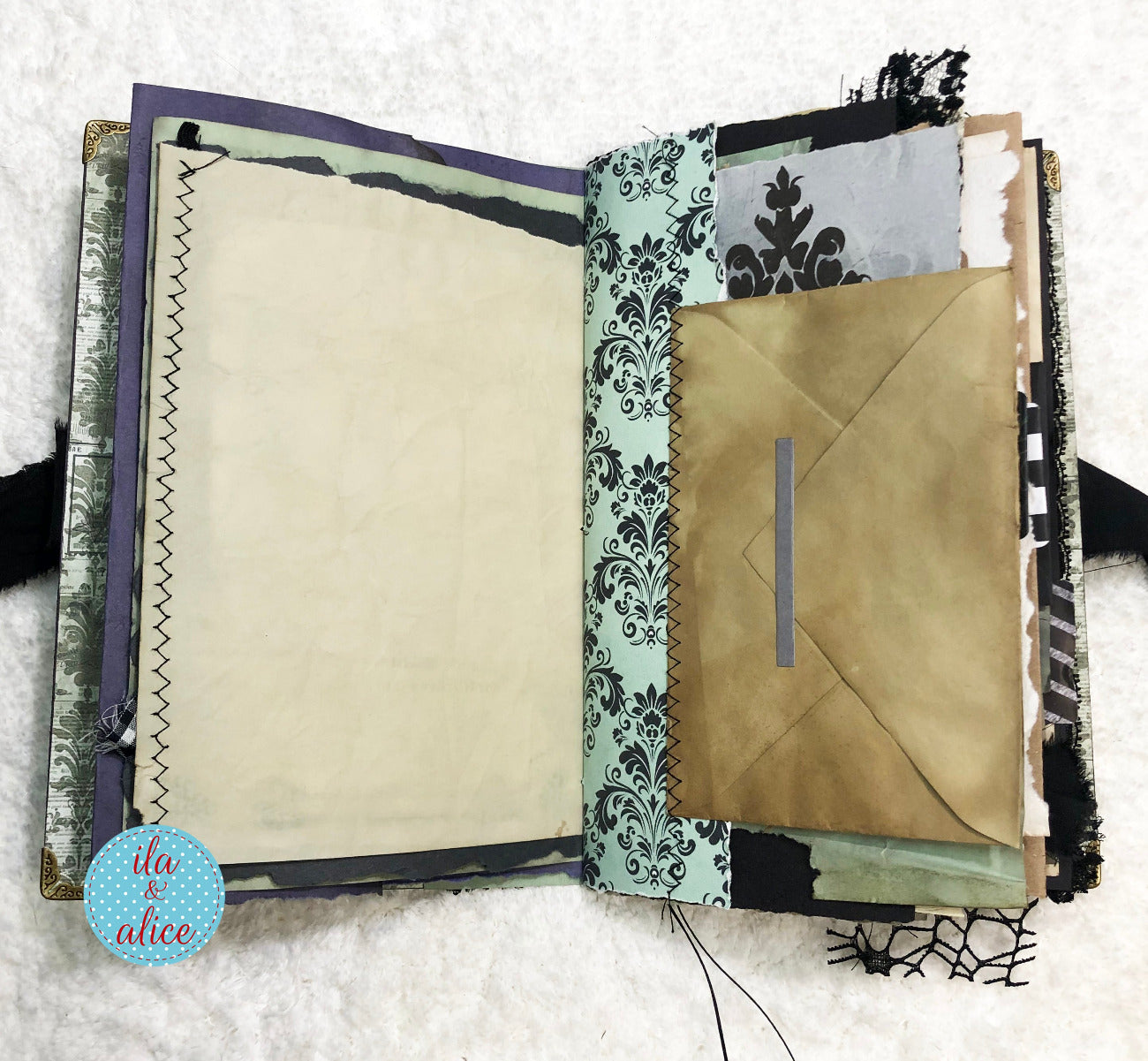 Handmade Eerie Halloween Gothic junk journal with decorative pages and a gold envelope on a textured surface