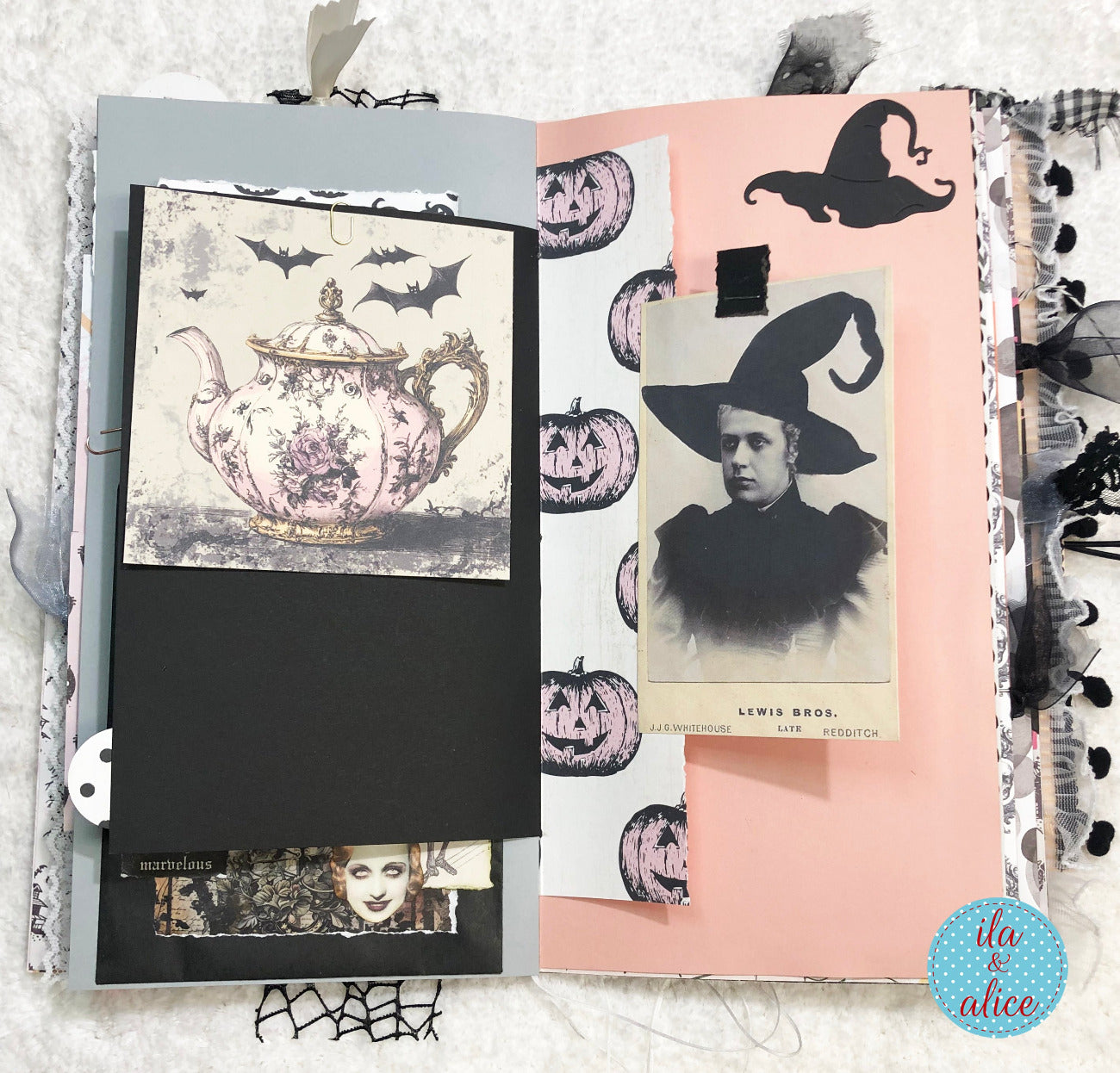 Handmade Pink and Black Halloween junk journal with stationery items including a notebook, postcard, and stickers on a textured surface.