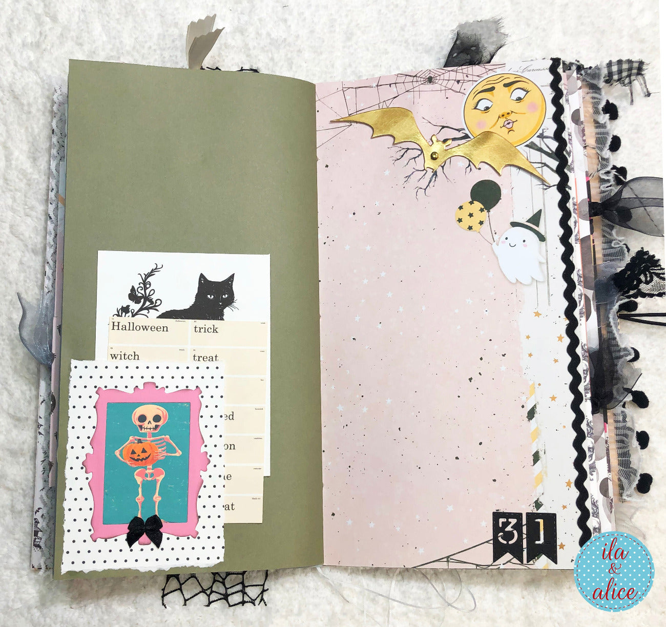 Handmade Pink and Black Halloween junk journal with Halloween-themed pages and decorations on a textured surface.