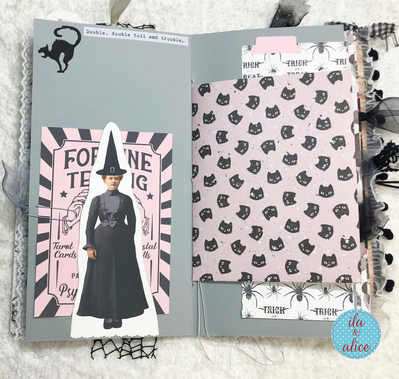 Handmade Pink and Black Halloween junk journal with bookmark, and patterned paper on a textured surface.