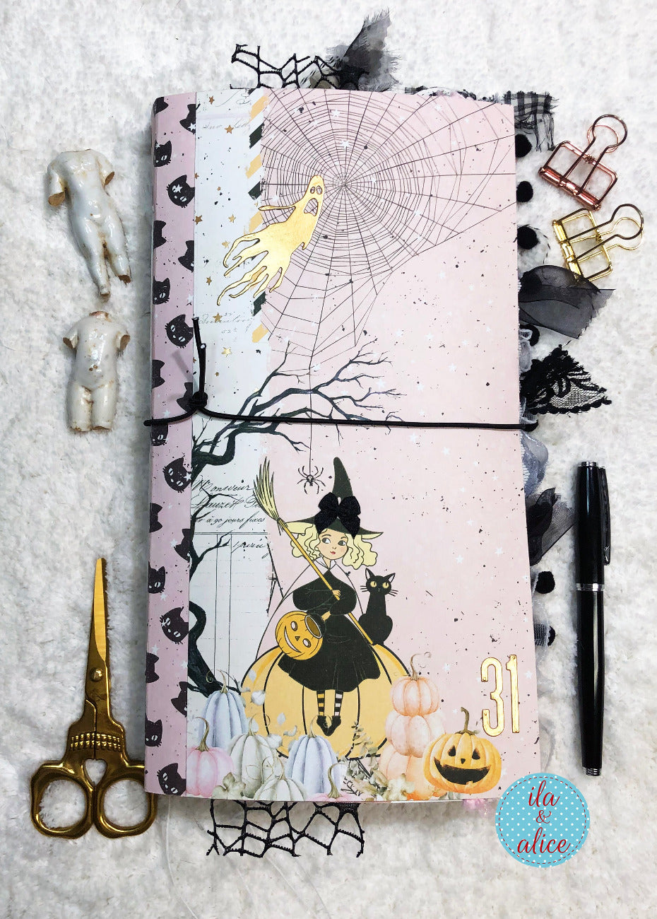 Handmade Pink and Black Halloween junk journal with cute witch and black w pumpkins on a textured surface.