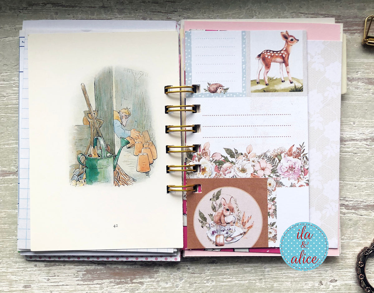 Planner with decorative stickers featuring illustrations of a fairy and a deer on a wooden surface.