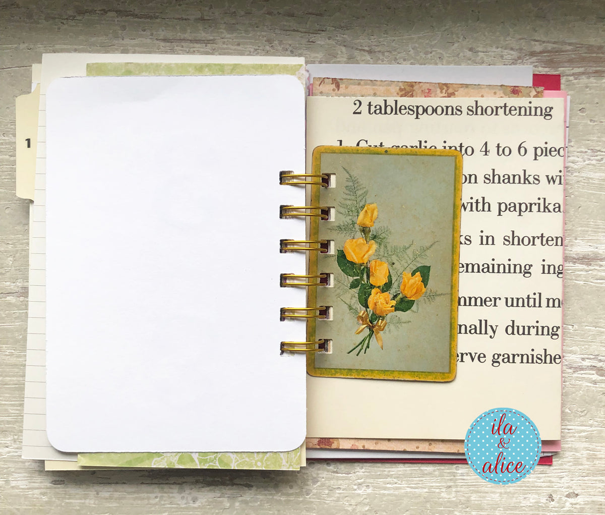 Open spiral-bound notebook with floral design on a wooden surface