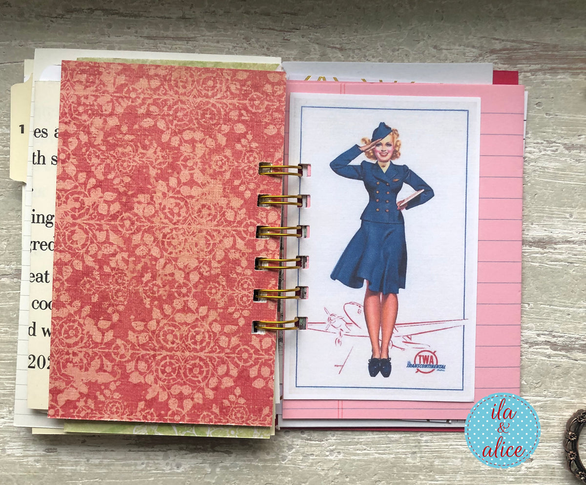 Notebook with a decorative cover and a page featuring a vintage-style illustration of a woman in a blue dress.