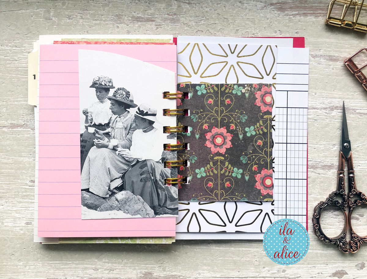 Notebook with floral design on a wooden surface with scissors and other items.