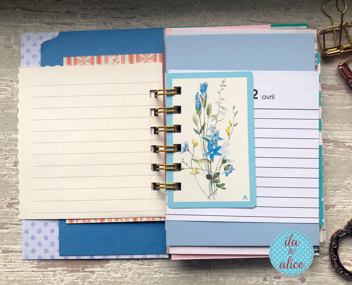 Planner with floral bookmark and colourful tabs on a wooden surface