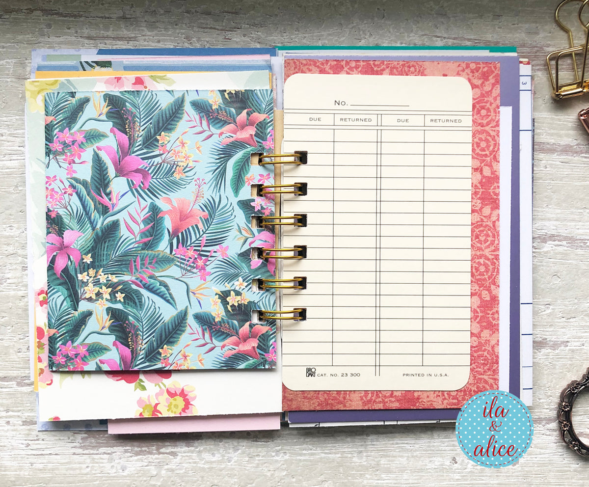 Planner with floral cover and pink and white pages on a wooden surface