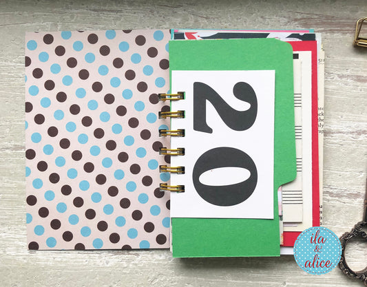 Planner with polka dot cover and a card displaying the number 20 on a wooden surface.