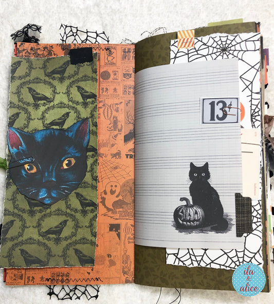 Handmade made Halloween junk journal  with Halloween-themed pages featuring a black cat and pumpkin.