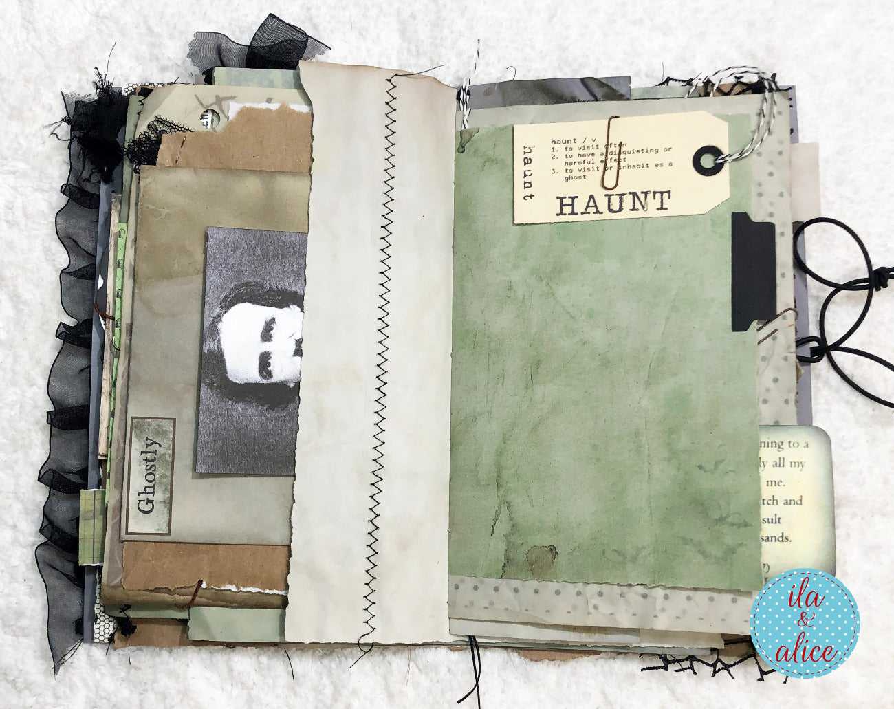 An open handmade mixed-media scrapbook journal featuring layered paper textures, black ruffled trim, a vintage-style portrait photo, and a green textured page with a 'HAUNT' label.