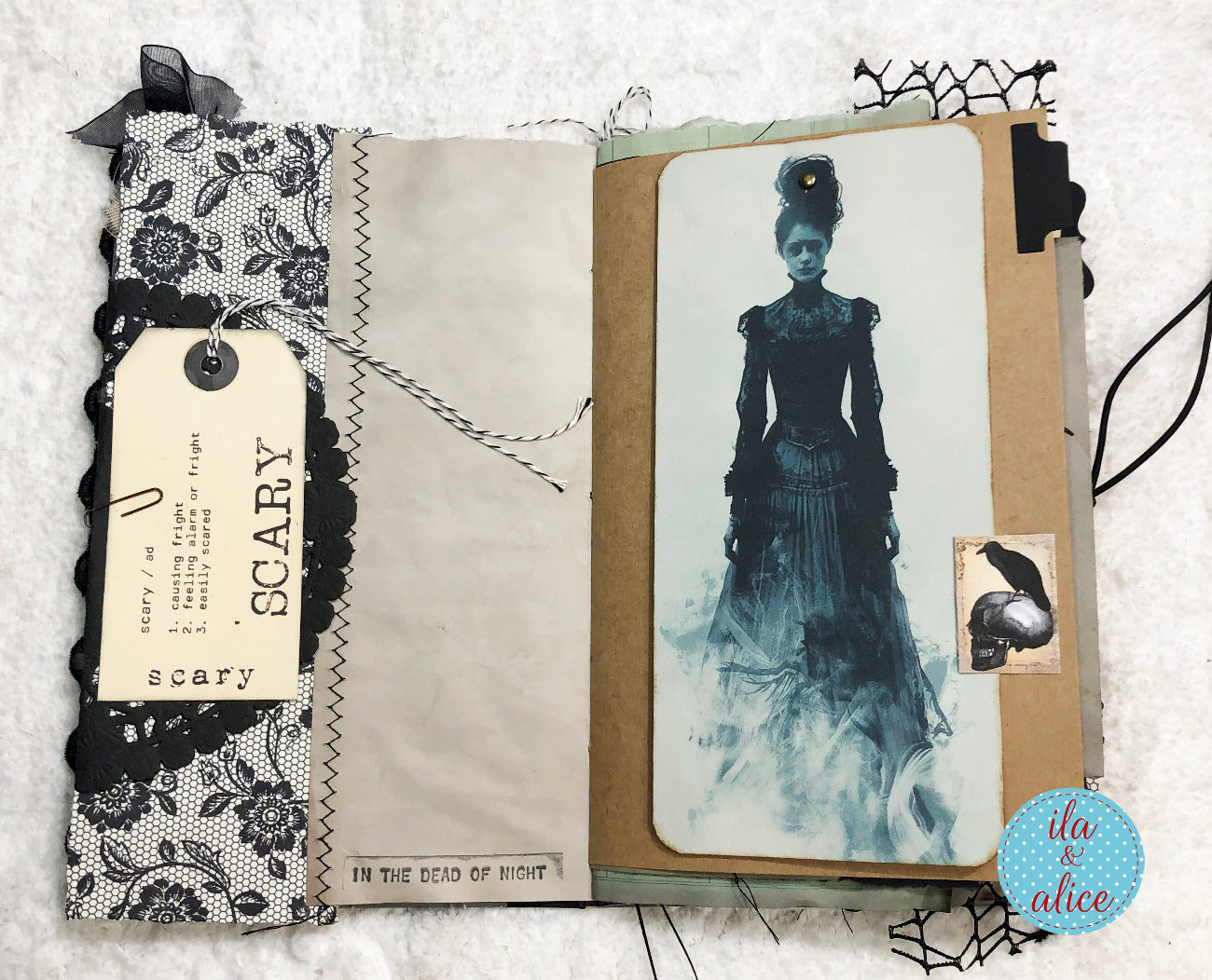 An open handmade scrapbook journal featuring a gothic collage design. The left page has a black and white lace patterned cover with a hanging paper tag that reads 'SCARY'.