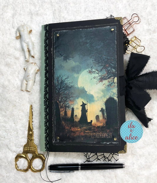 Handmade Eerie Halloween Gothic junk journal  with a Halloween-themed cover, surrounded by decorative items on a textured surface.