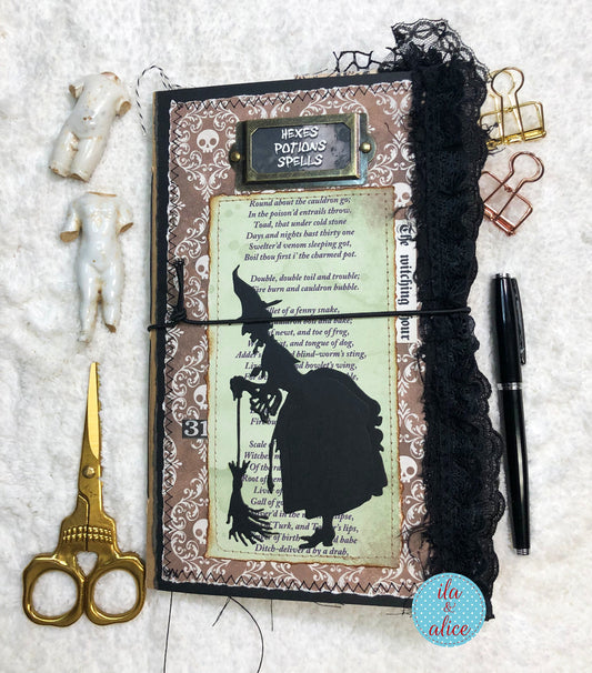 Handmade Halloween junk journal with witch silhouette and text, surrounded by decorative items on a textured surface.
