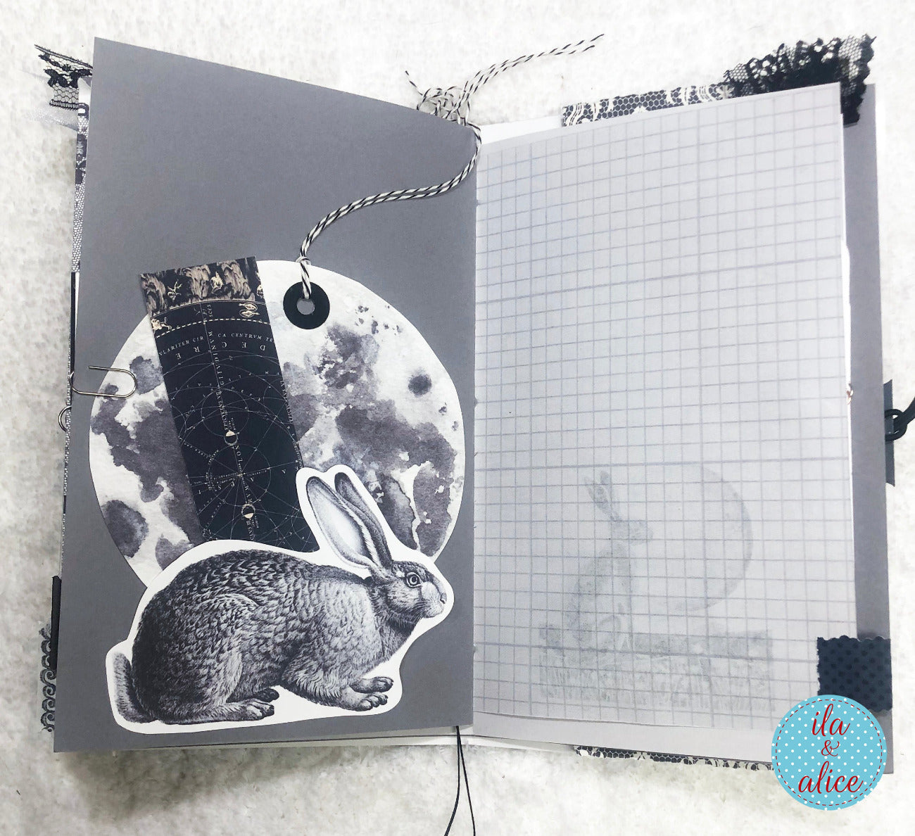 Handmade junk journal with full moon and hare, illustration and grid page on a textured surface