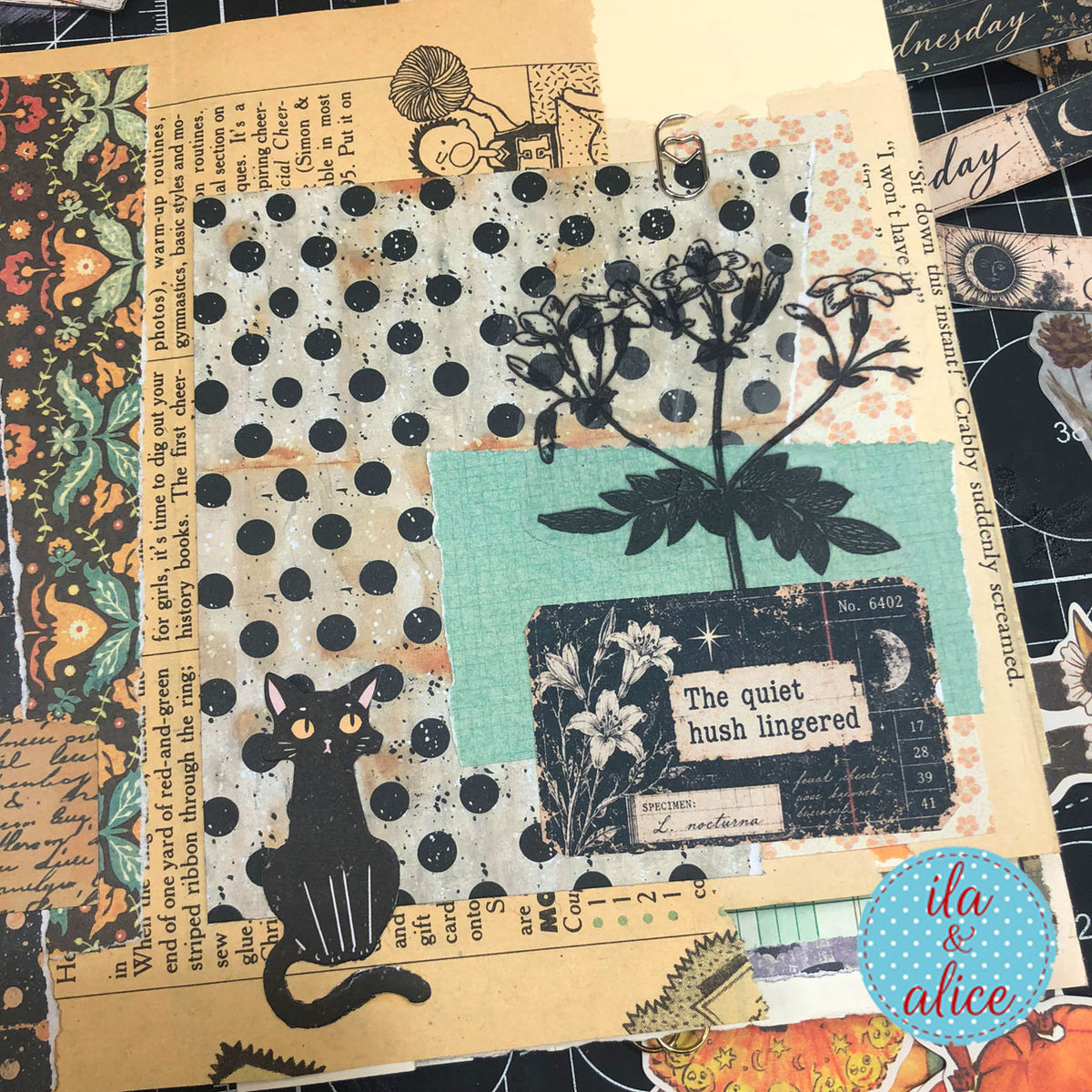 Layered journal page with a black cat, botanical papers, and Midnight Findings “The quiet hush lingered” ephemera card.