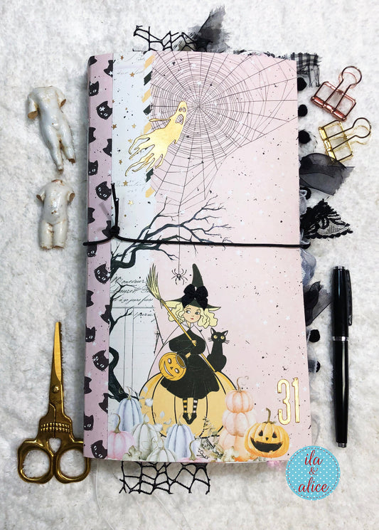 Handmade Pink and Black Halloween junk journal  with cute witch and black w pumpkins on a textured surface.
