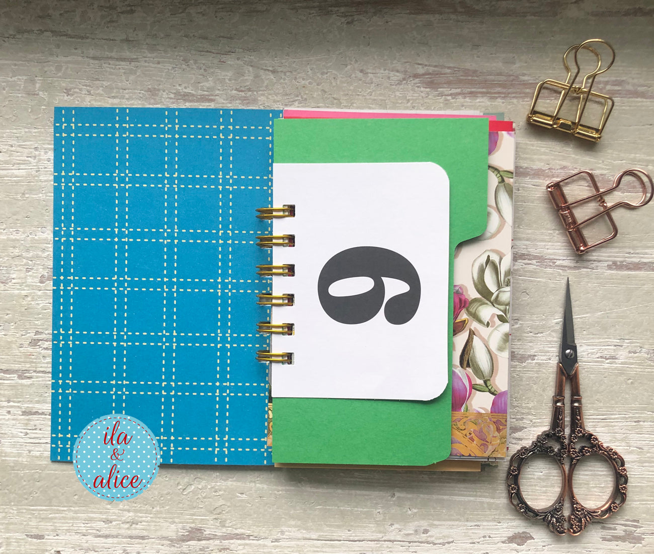 Inside Mini junk journal with wide-eyed cat illustration on blue background, handmade vintage-style notebook with spiral binding