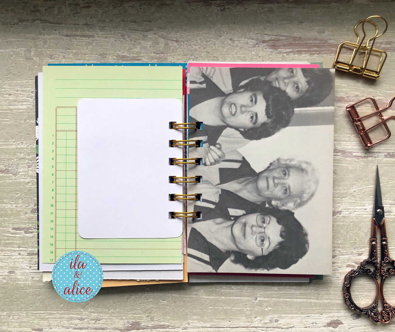 Open notebook with vintage photo of a cafeteria ladies from the 80s  on a wooden surface with scissors and clips.
