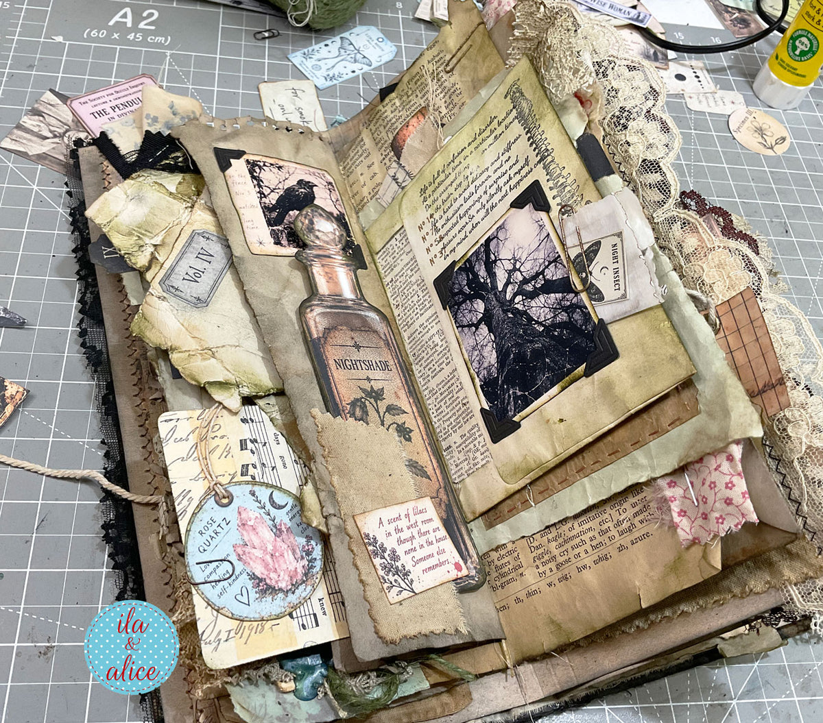 Witch’s grimoire spread featuring a Nightshade potion bottle, eerie tree photograph, night insect card, rose quartz tag, lace and aged papers.