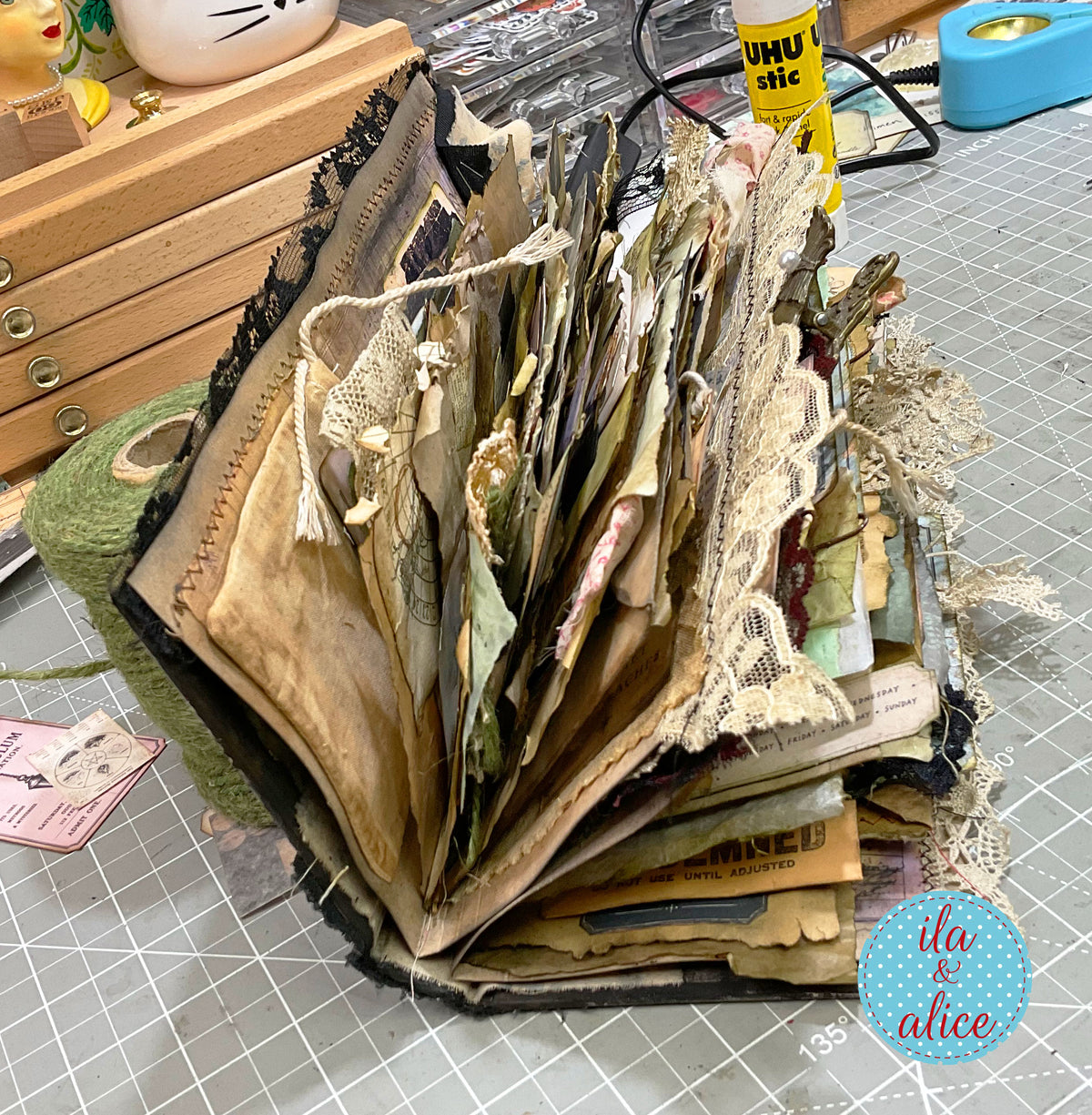 Side view of the thick handmade witch’s grimoire showing its many layered pages, pockets, torn papers, textiles, lace and dimensional ephemera.