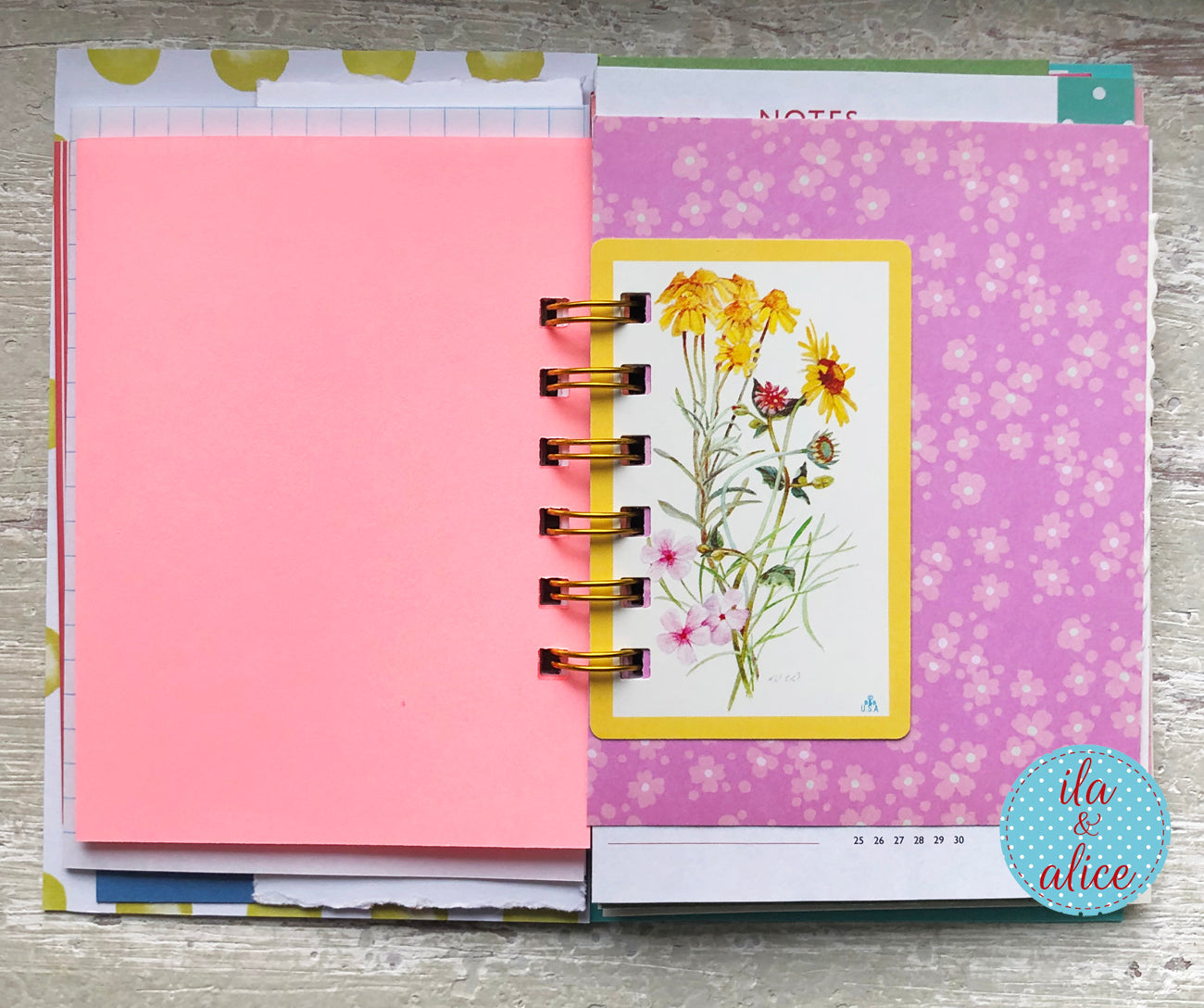 Planner with pink cover and floral design on a wooden surface