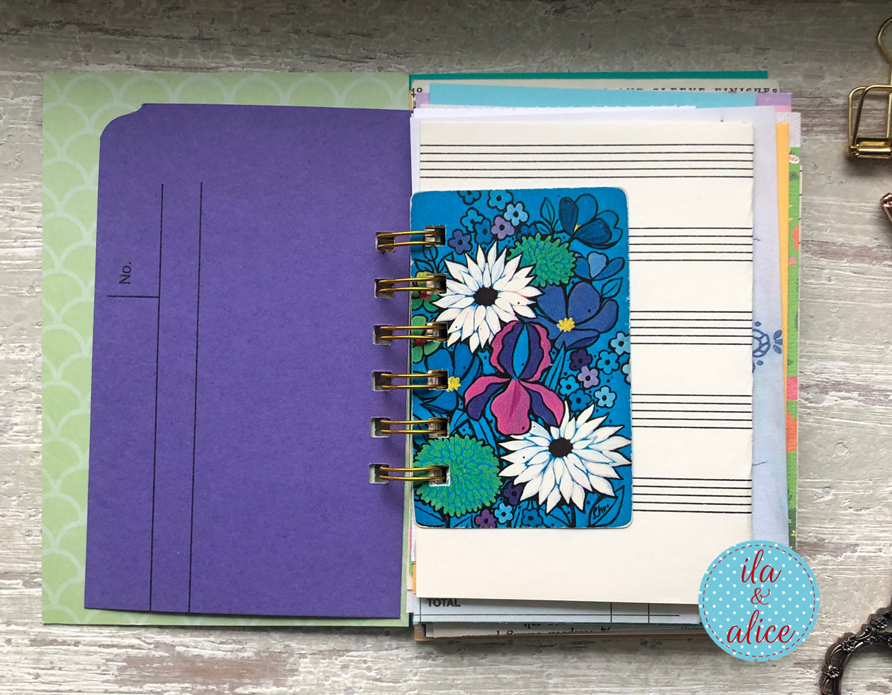 Planner with floral design on a wooden surface, featuring the brand 'ila and alice'.