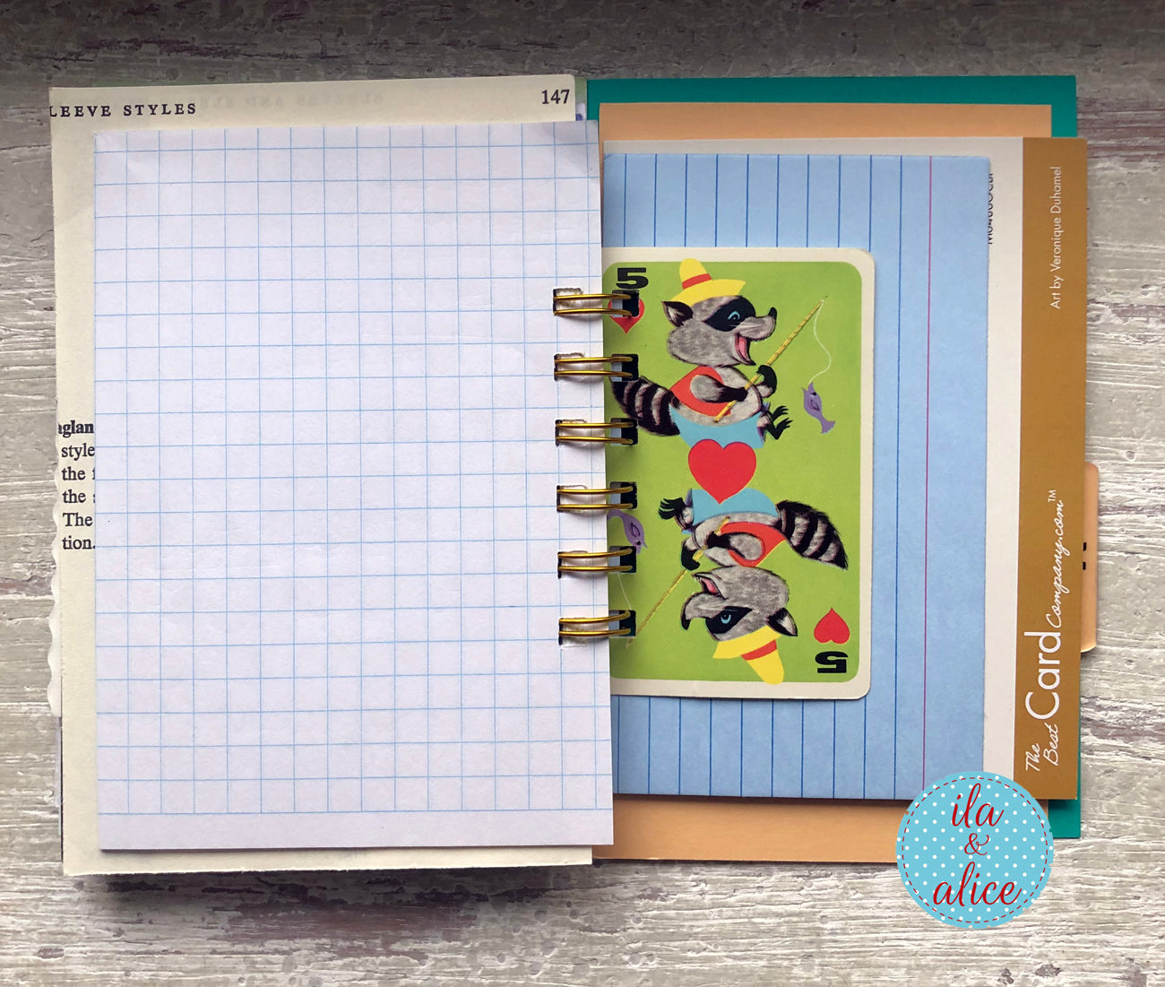 Planner with a decorative card featuring a raccoon illustration on a wooden surface.