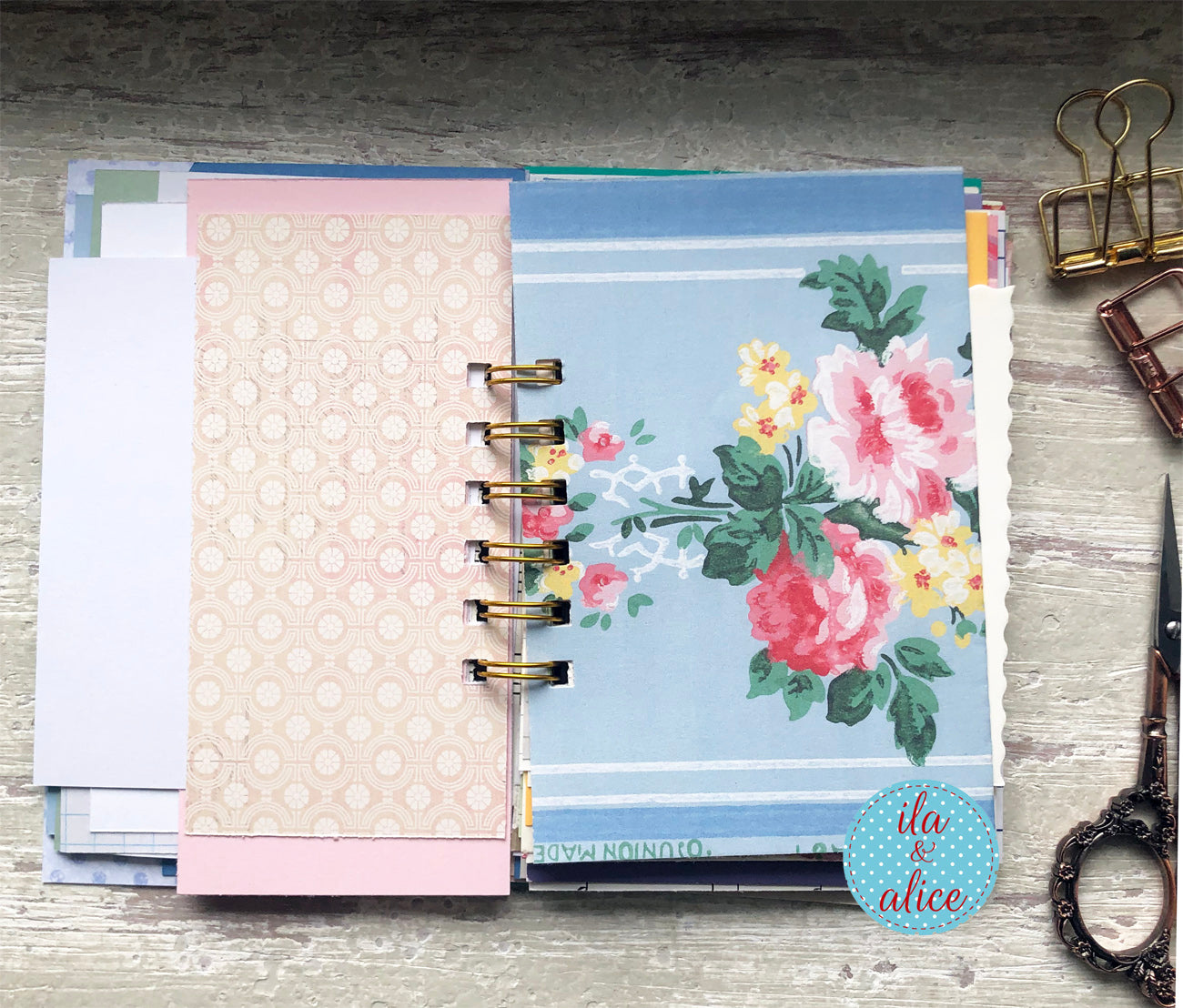 Planner with floral design on a wooden surface with stationery items.