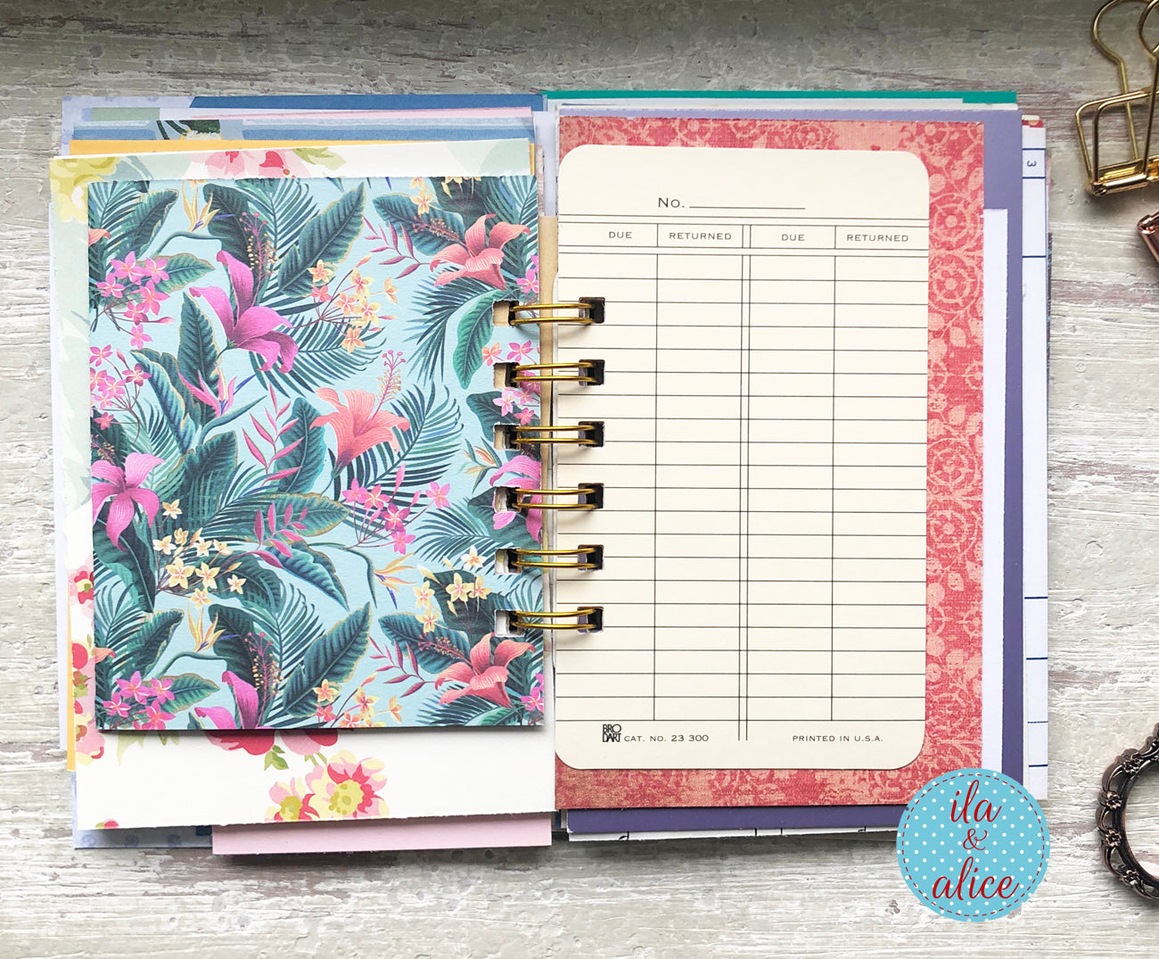 Planner with floral cover and pink and white pages on a wooden surface