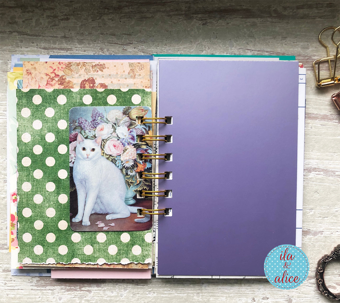 Open planner with decorative pages featuring a cat and floral design, on a wooden surface.