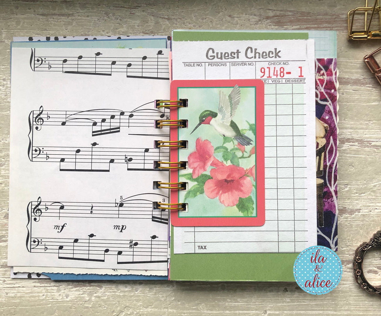 Planner with music sheet, floral design, and check stub on a wooden surface.