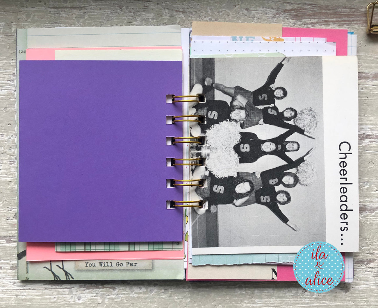 Planner with colourful pages and a black and white photo of cheerleaders on a wooden surface.
