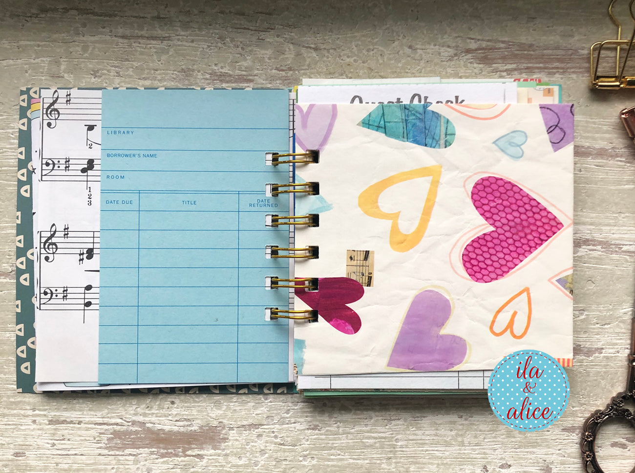 Two planners open to different pages on a wooden surface, one with music notes and the other with colorful hearts.