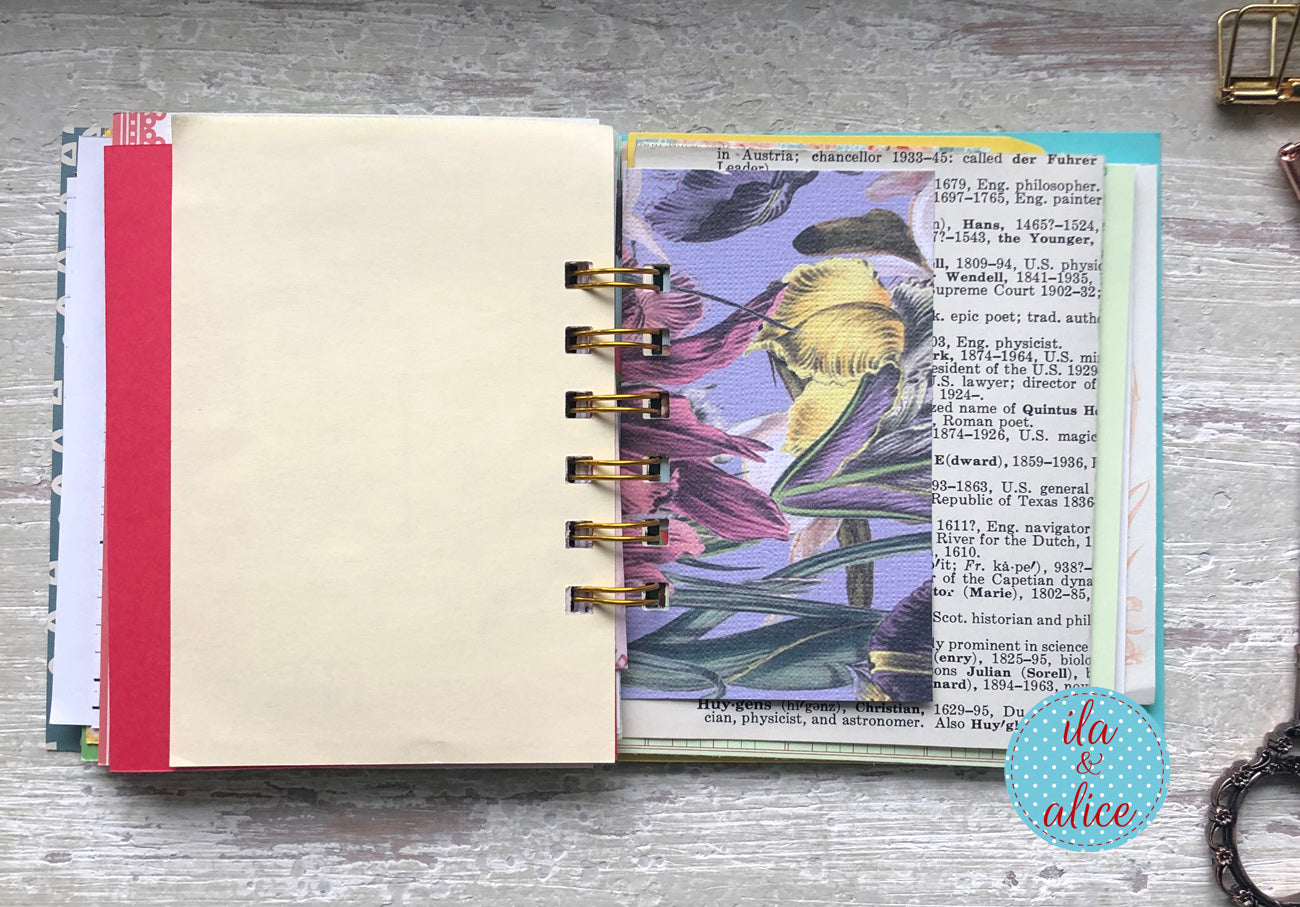 Open planner with decorative pages on a wooden surface, featuring the brand 'ila alice'.
