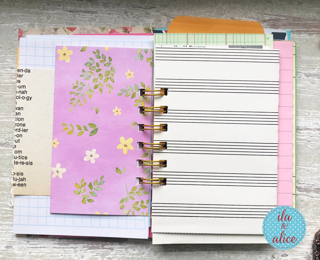 Planner with floral and lined pages on a wooden surface, featuring the brand 'ila & alice'.